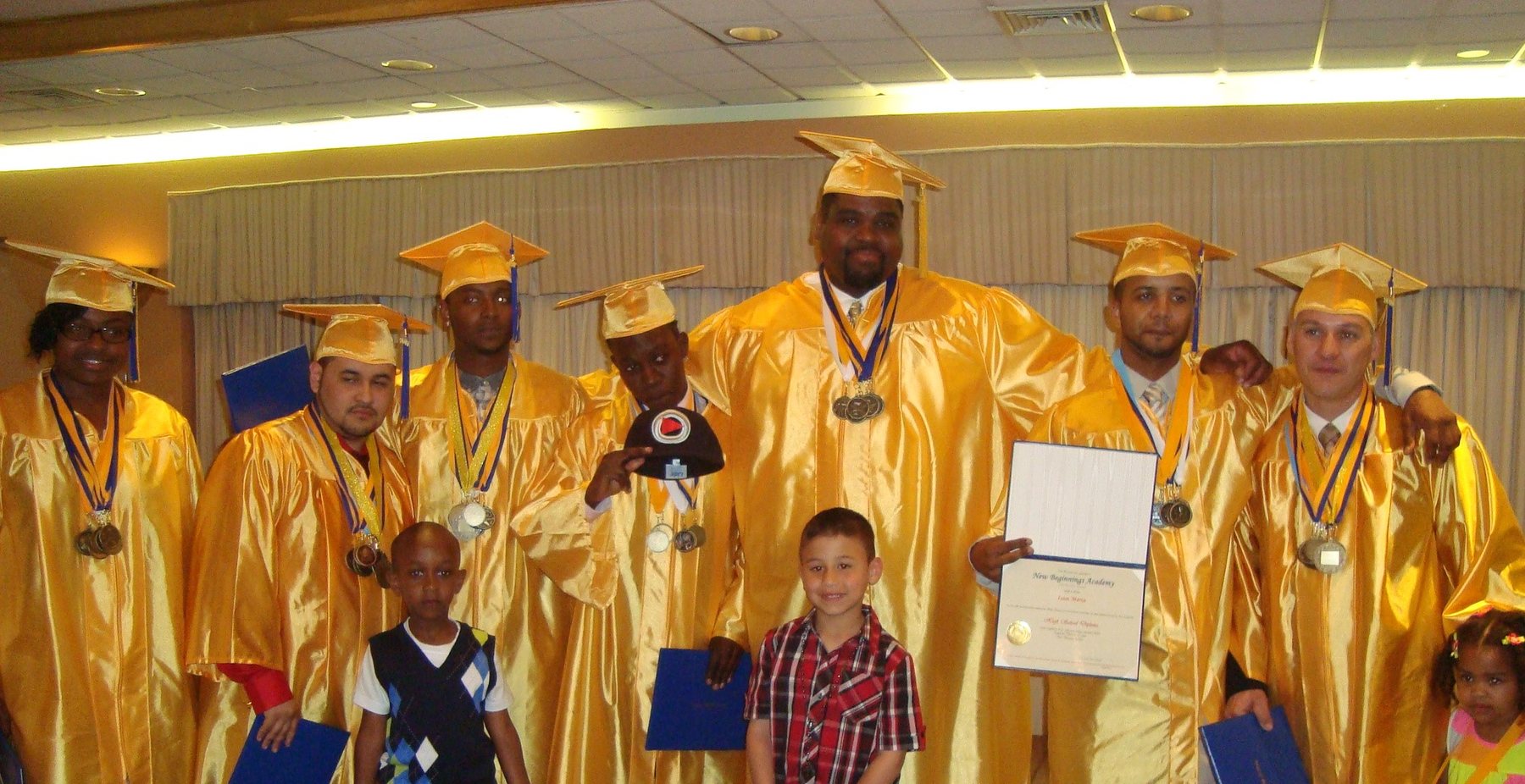 Graduates in gold caps and gowns with family and staff