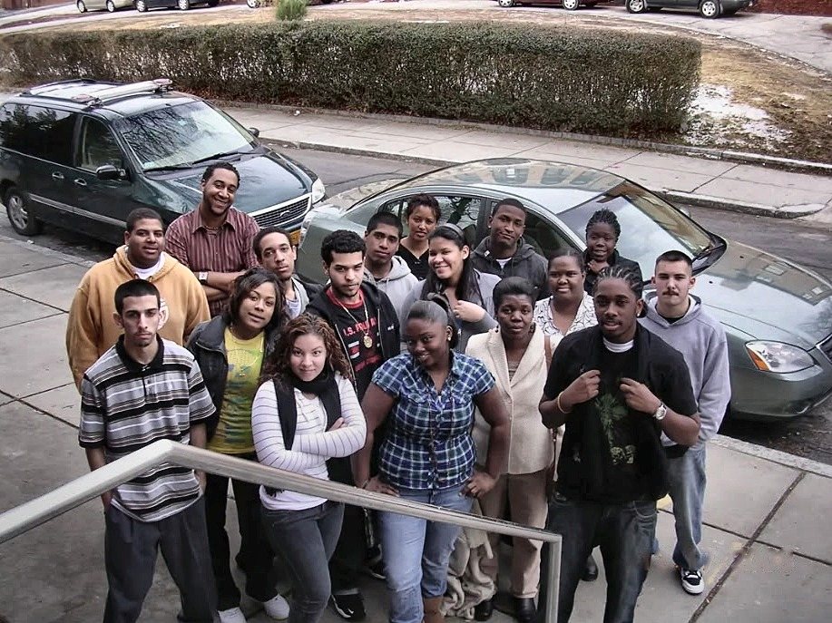 A class of the Excel High School Diploma Program standing together on the sidewalk in front of the school