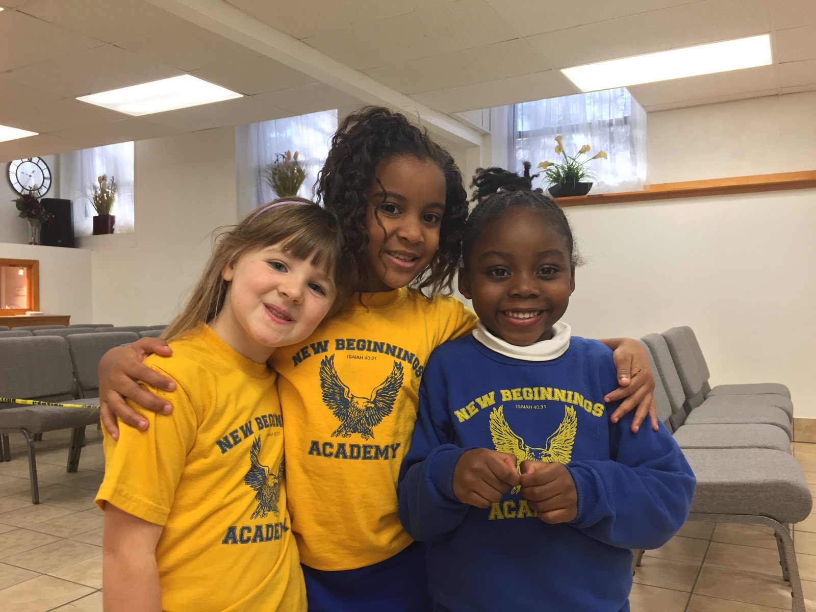 Three students in New Beginnings Academy shirts, arms around each other